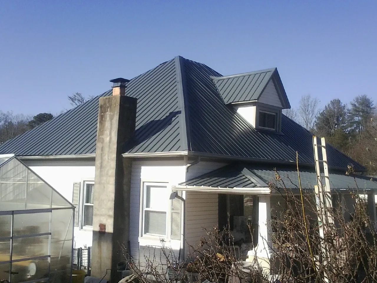 Dark blue standing seam metal roof on a white farmhouse with dormer — Slate & Tile Roof Repair by Roofing Brothers in Shepherdsville