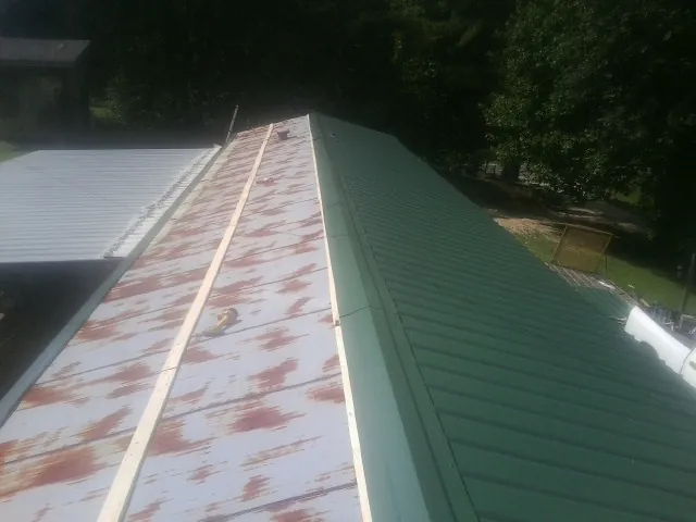 Old rusted panels beside newly installed green metal roofing — Wind Damage Roof Repair by Roofing Brothers in Shepherdsville