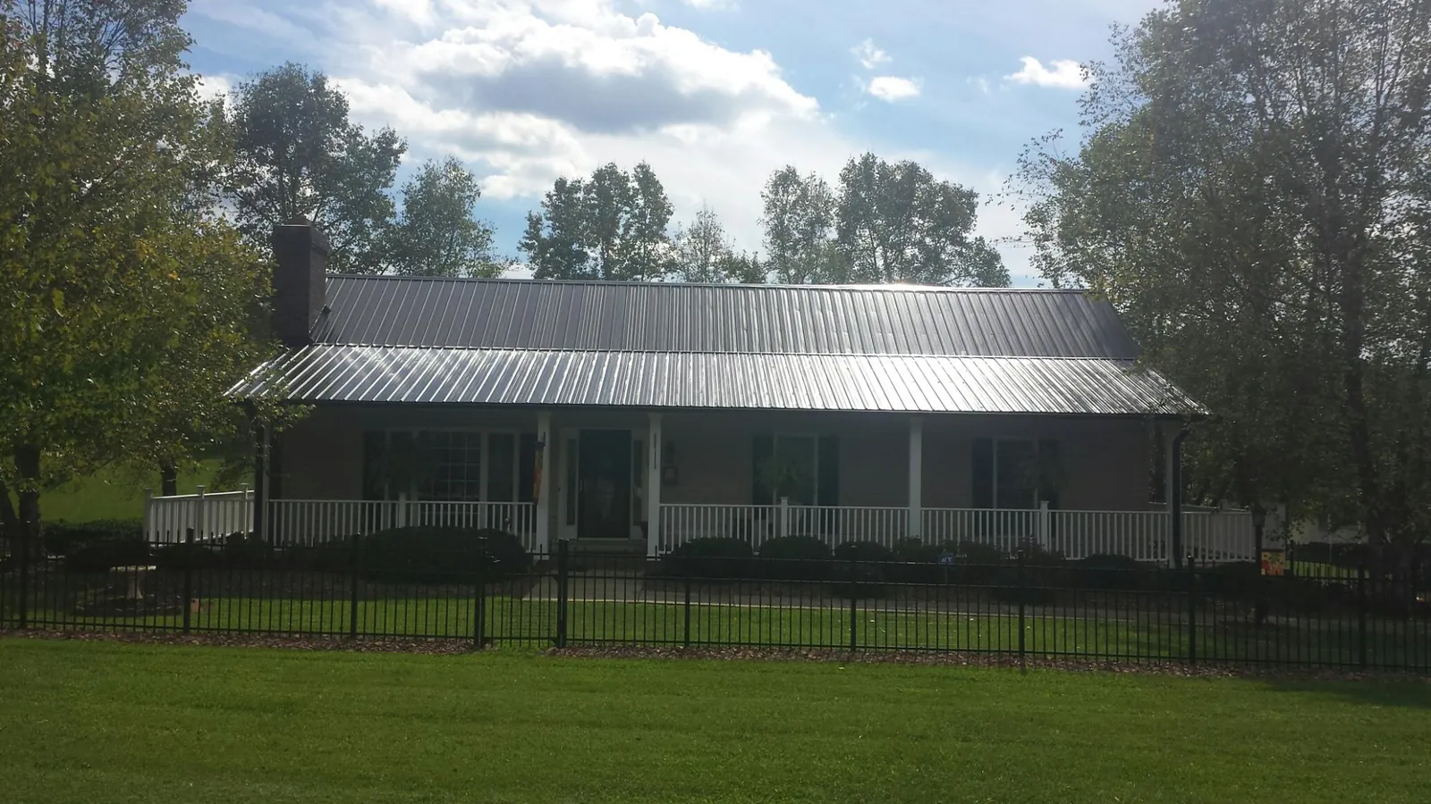 Gray metal roof on a brick ranch with a full width front porch — Gutter Guard Installation work by our crew in Shepherdsville