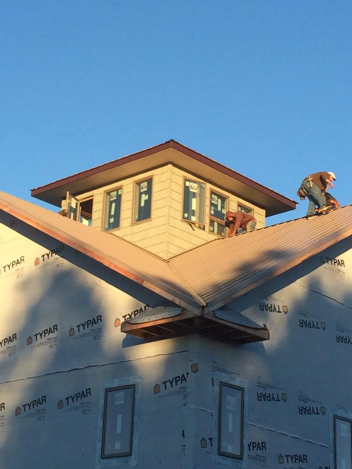 Roofers working around a rooftop cupola on a new metal roof at sunset — Roof Waterproofing in Shepherdsville by Roofing Brothers